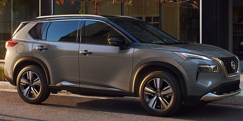 A silver Nissan Rogue parked on a city street